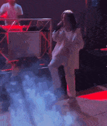 a woman is singing into a microphone in a dark room