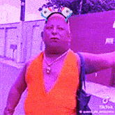 a man wearing an orange tank top and a purple headband is walking down a street .