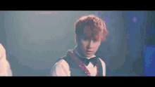 a man with red hair is wearing a bow tie and a vest .