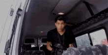 a man is standing in the back of a van holding a gun .