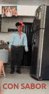 a man with a red bow on his head is standing in front of a refrigerator with the words con sabor written on the bottom