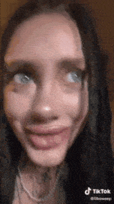 a woman with dreadlocks is making a funny face with her tongue hanging out .