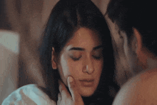 a man is touching a woman 's face in a bedroom .
