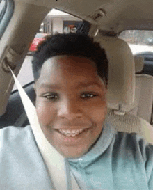 a young boy is sitting in the driver 's seat of a car and smiling .