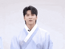 a man in a blue kimono is dancing with his arms outstretched .