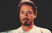 a man with a beard and a white shirt is looking at the camera