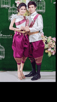 a man and a woman are posing for a photo with the word romance on the bottom right