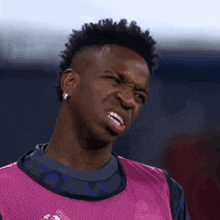 a man with a mohawk making a funny face and wearing a pink vest
