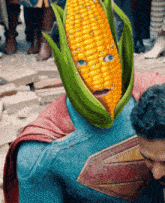 a man in a superman costume has a corn on the cob instead of his face