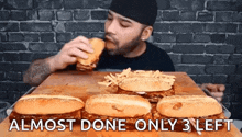 a man is eating a hamburger and french fries on a table .