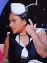 a woman is wearing a sailor hat and giving a middle finger