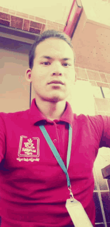 a man wearing a red polo shirt with a foreign language on the front takes a selfie