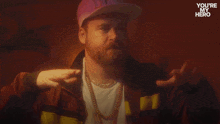 a man with a beard wearing a hat and a jacket with the words " you 're my hero " on it