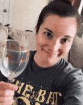 a woman in a t-shirt is holding a wine glass and smiling .