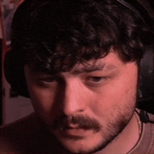 a man with a beard wearing headphones is looking at the camera .