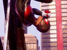 a man in a spiderman costume is hanging upside down on a pole