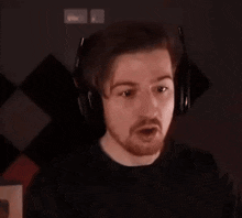 a man with a beard is wearing headphones while sitting in front of a computer .