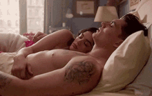 a shirtless man and woman are laying in bed