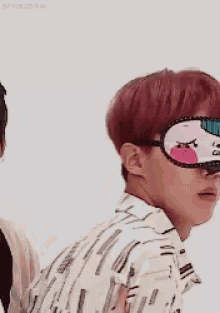 a man with red hair is wearing a sleep mask with a face on it