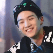 a close up of a person wearing a black hat and sunglasses smiling .