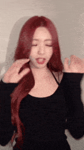 a woman with red hair is wearing a black sweater and making a funny face .