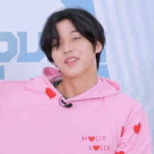 a young man wearing a pink hoodie with holly written on the front