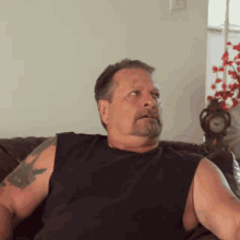 a man sitting on a couch with a clock in the background