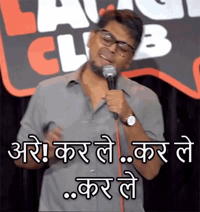 a man is holding a microphone in front of a laugh club sign .