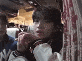 a young man in a ny jacket is sitting in a bus