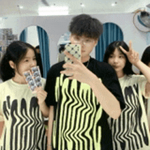 a group of people are taking a selfie in front of a mirror