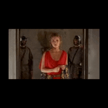 a woman in a red dress standing in front of a door