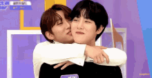 two young men hugging each other on a purple background .