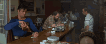 a man in a superman costume is sitting at a bar
