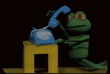 a stuffed frog is talking on a blue telephone