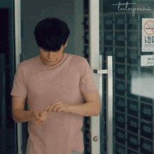 a man in a pink shirt is standing in front of a door with a sign on it that says " no smoking "