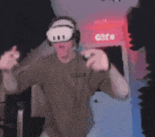 a man wearing a virtual reality headset and headphones is dancing in a dark room .