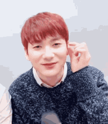 a young man with red hair is wearing a sweater and smiling