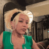 a woman with blonde hair and a green tank top has a tattoo on her chest that says " i love you "