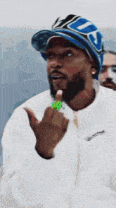 a man with a beard wearing a blue hat and a white jacket is giving the middle finger