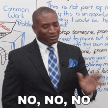 a man in a suit and tie says no no no in front of a whiteboard