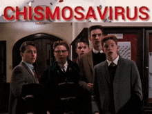 a group of young men are standing in front of a sign that says chismosaurus