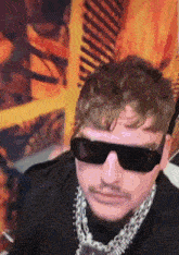 a close up of a man wearing sunglasses and a chain around his neck