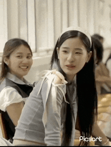 a girl with long hair is smiling next to another girl
