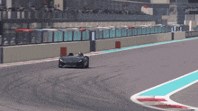 a black sports car is driving on a track with a blue line