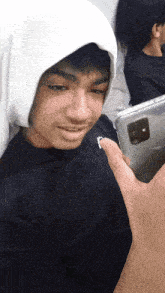 a man wearing a black shirt and a white hoodie holds a cell phone