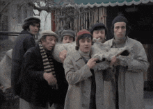 a group of men wearing hats and scarves are holding a large blanket