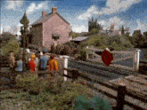 a group of people are walking across a railroad crossing with a stop sign in the foreground