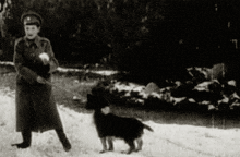 a black and white photo of a man walking a small dog