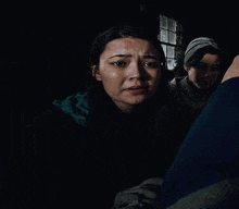 a woman is looking at the camera in a dark room while a man is standing behind her .