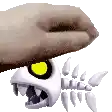 a hand is holding a skeleton of a fish with a yellow eye .